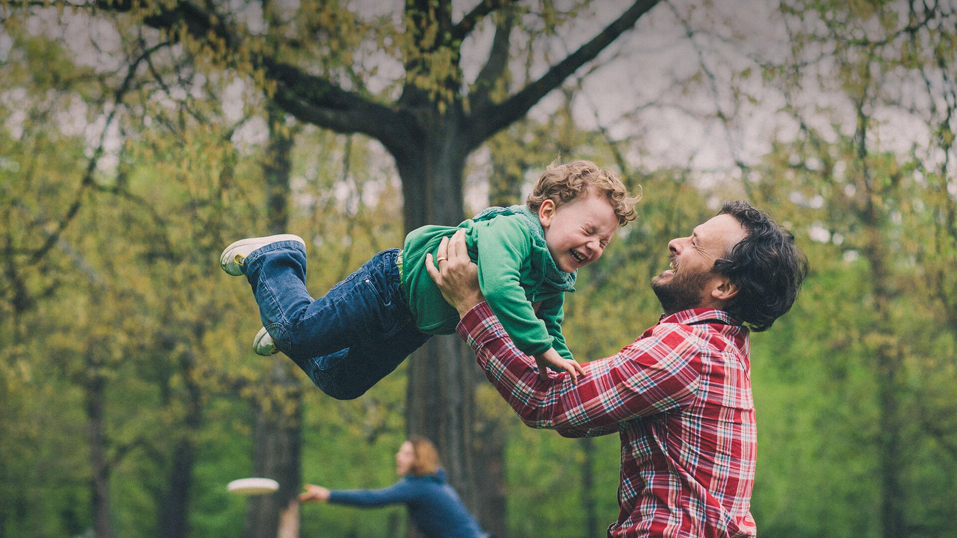 Single parents dating symbolized by a single dad who is tossing his little son in the air on a playground