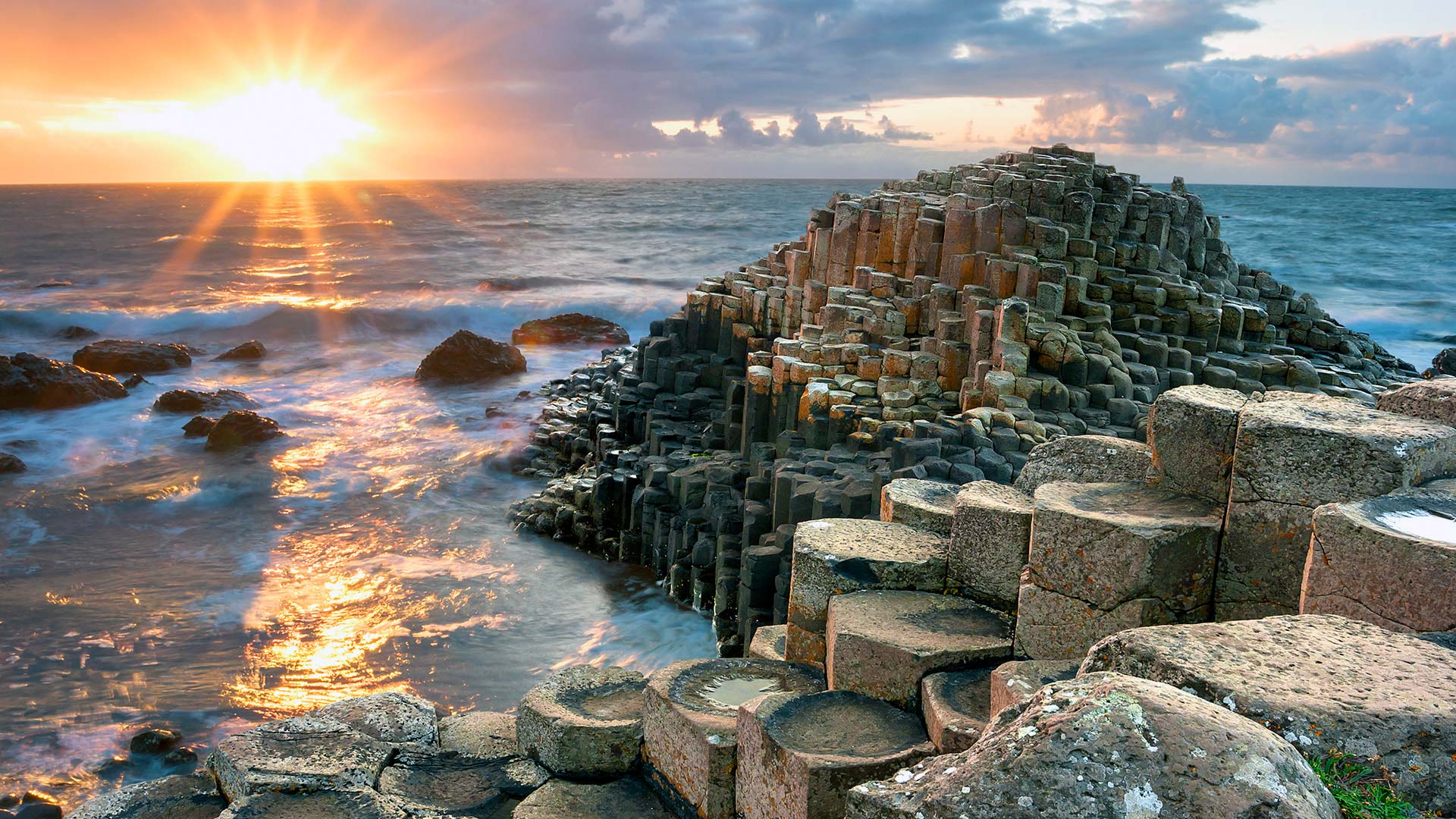 Giant’s Causeway coastline at sunrise with dramatic basalt rock formations.