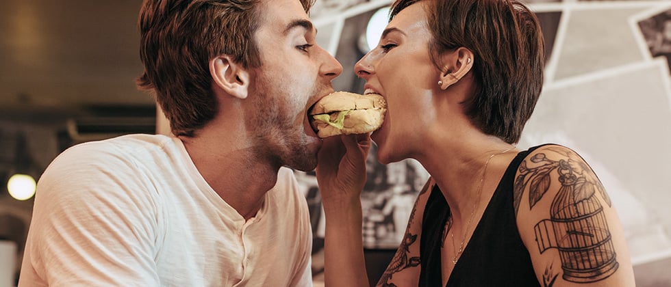 A young couple share a burger in a restaurant
