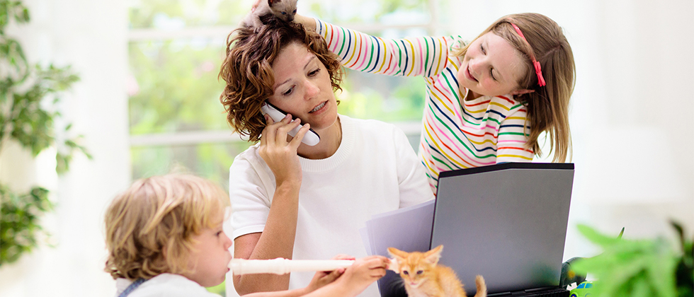 A woman trying to work at a computer, but two kids are distracting her