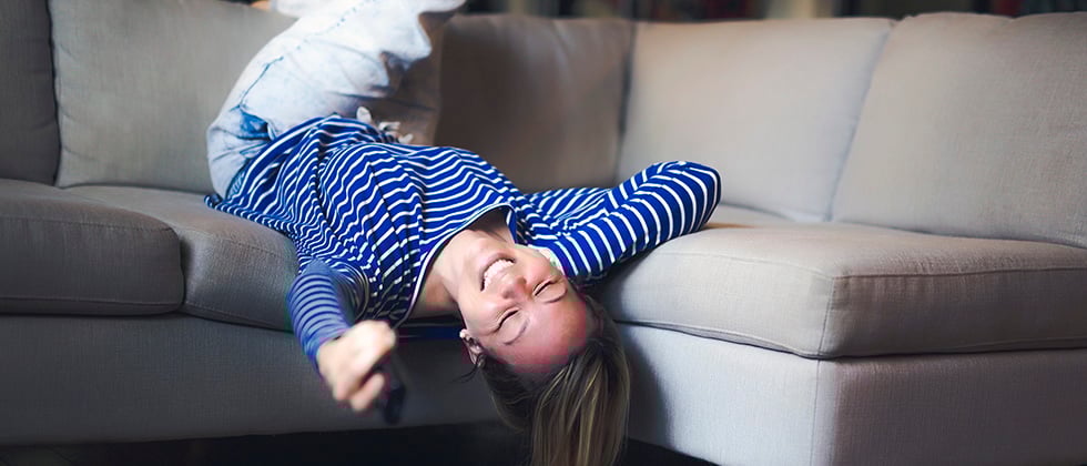 A woman sprawls on a sofa, her head hanging over the front edge