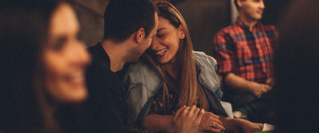 Man and woman lie in each other's arms and laugh as example of dating mindset