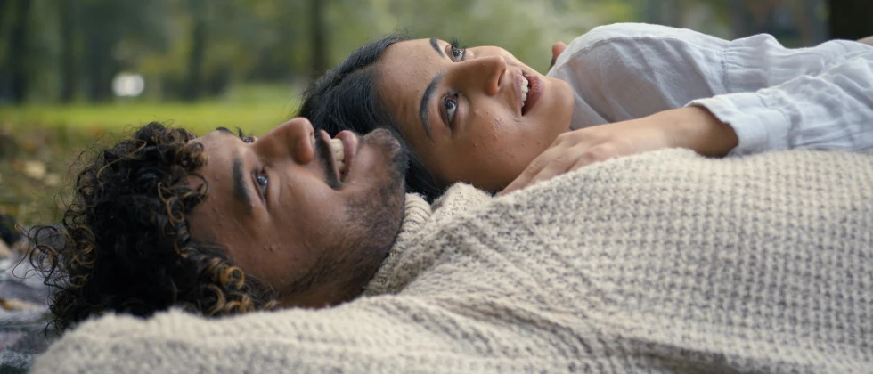 Couple laying in a park looking at the sky and cuddling.