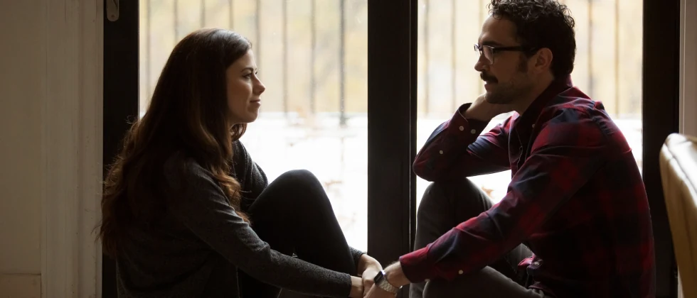 Broken up couple sitting at the window talking about their past.