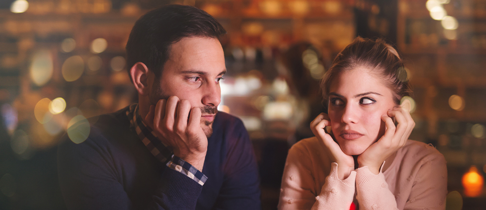 A couple in a cafe looking seriously at each other