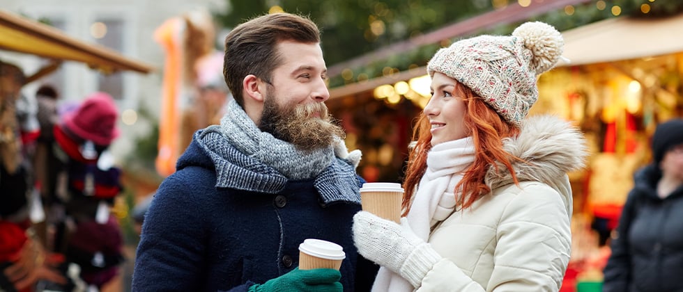 A couple dressed for cold weather smile at each other in the winter market