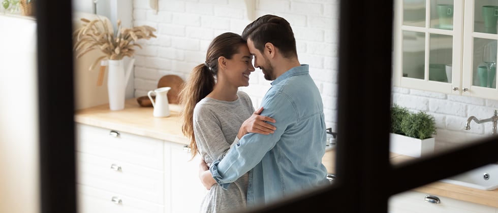 A couple dancing in a kitchen and smiling at each other