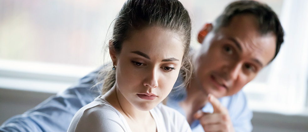 A man aggressively confronts his partner, who looks away from him