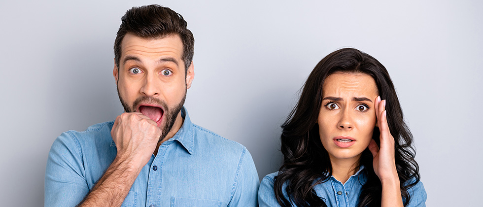 A similarly dressed couple look to camera with an expression of surprise