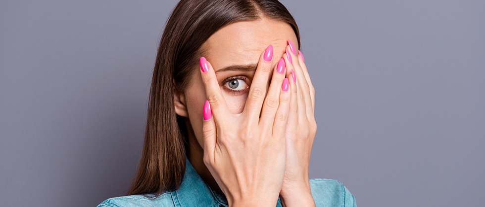 A woman looks through her fingers in embarrassment