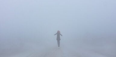 Someone standing at a distance in the middle of a foggy street