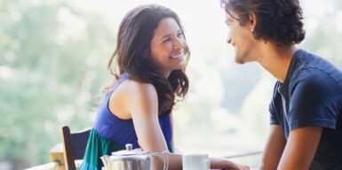 Young couple on a date outside smiling and laughing over coffee