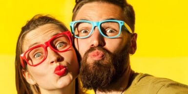 A couple being goofy wearing multi-colored glasses