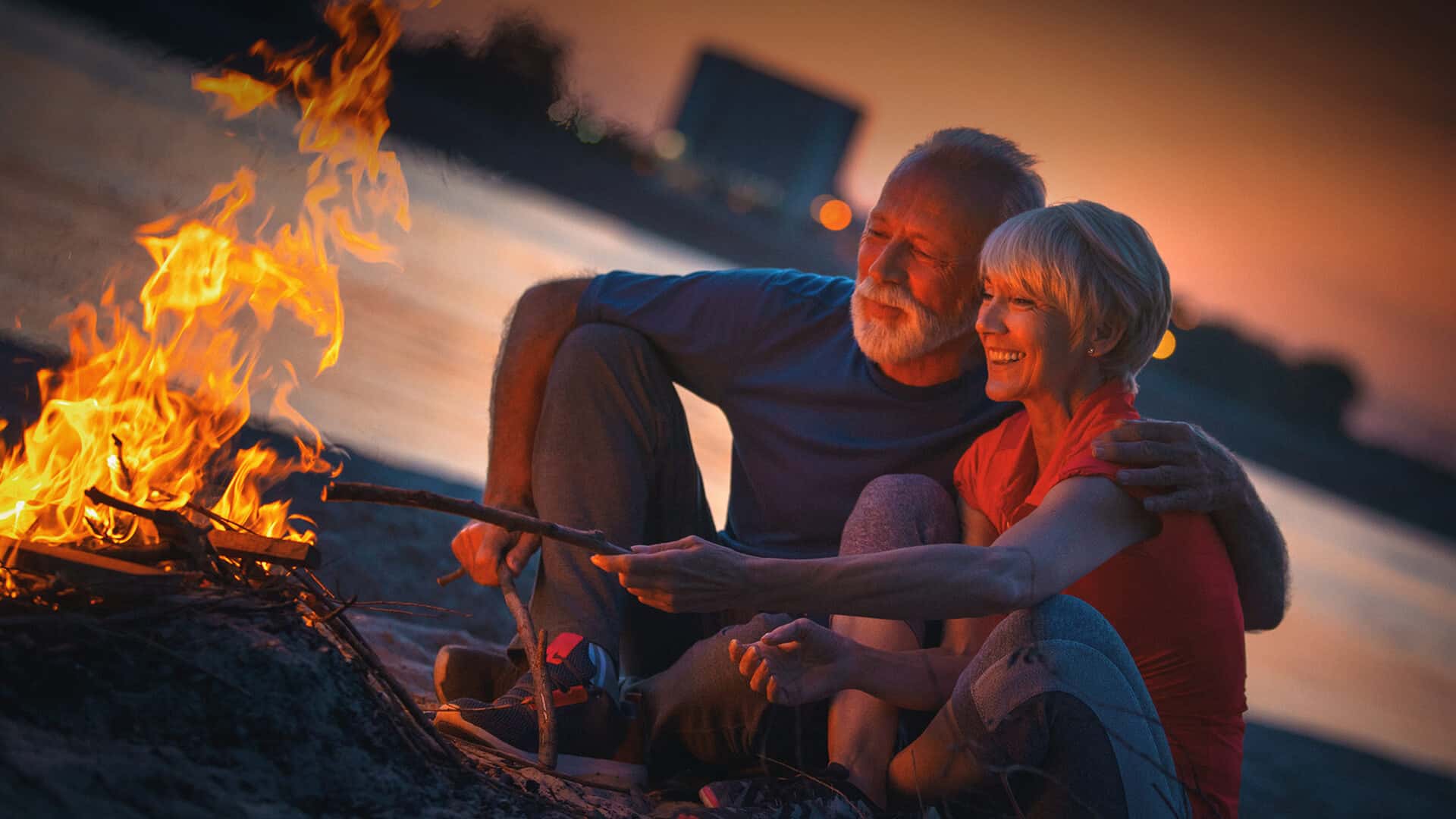 60s dating symbolized by a happy couple sitting in front of a campfire in UK