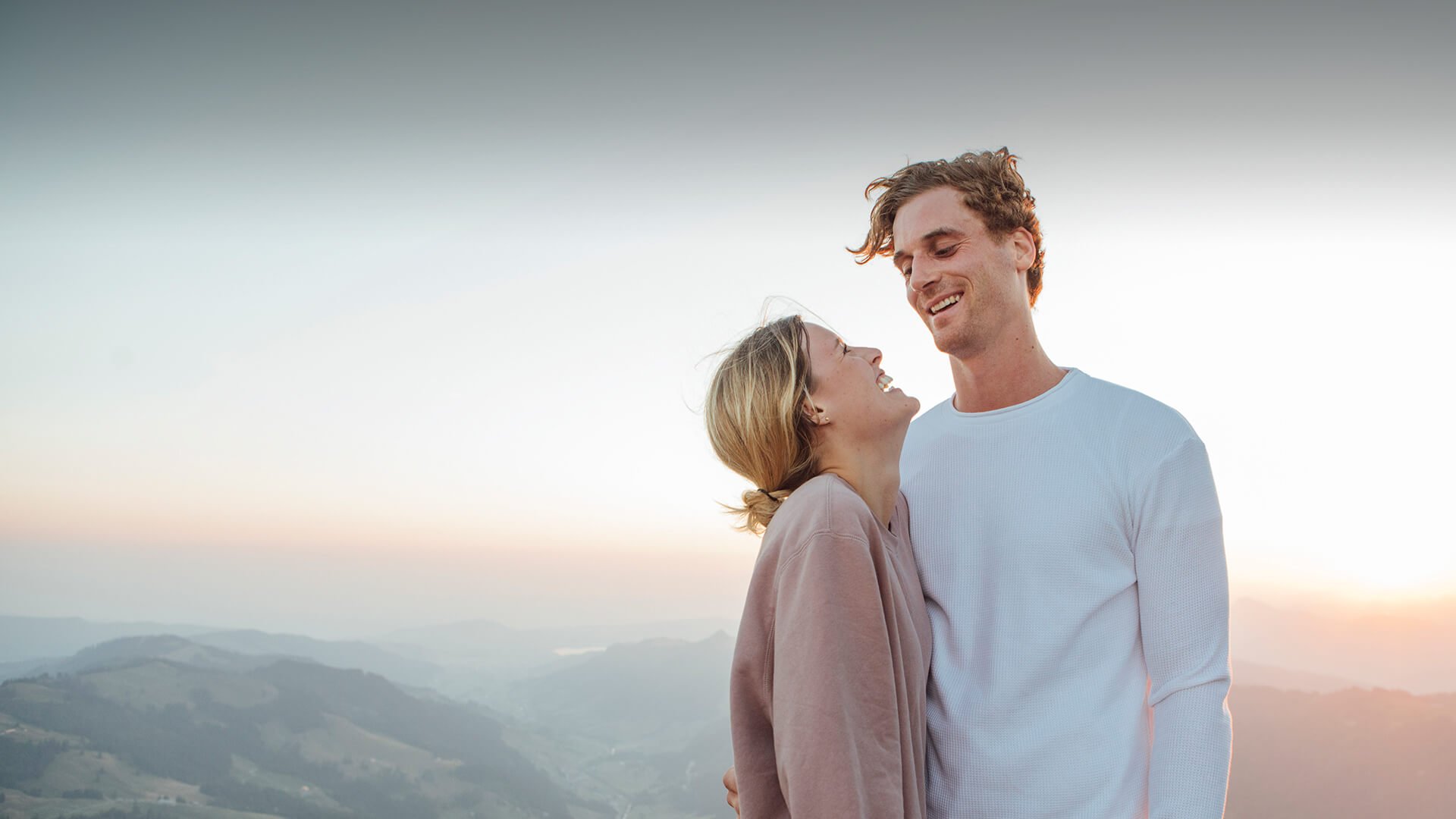 Divorced dating symbolized by a man and woman who stand close to each other in front of a romantic landscape