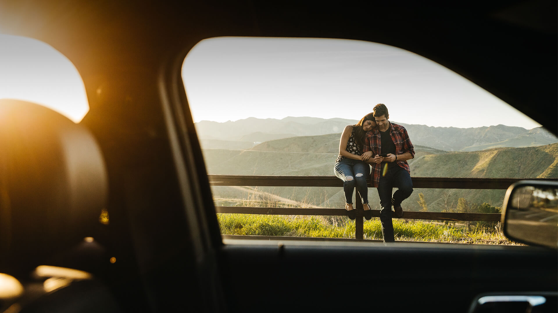 Lifestyle dating symbolized by a man and woman leaning at the fence and feeling in love with eatch other in front of a beautiful landscape in UK