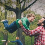 Single parent dating symbolized by a single dad who is tossing his little son in the air on a playground in UK
