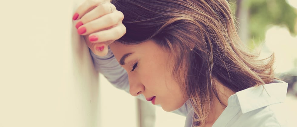 Frustrated woman leaning against a wall with her eyes closed