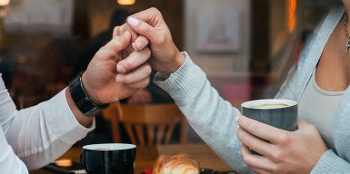 A couple hold hands over a table in a cafe
