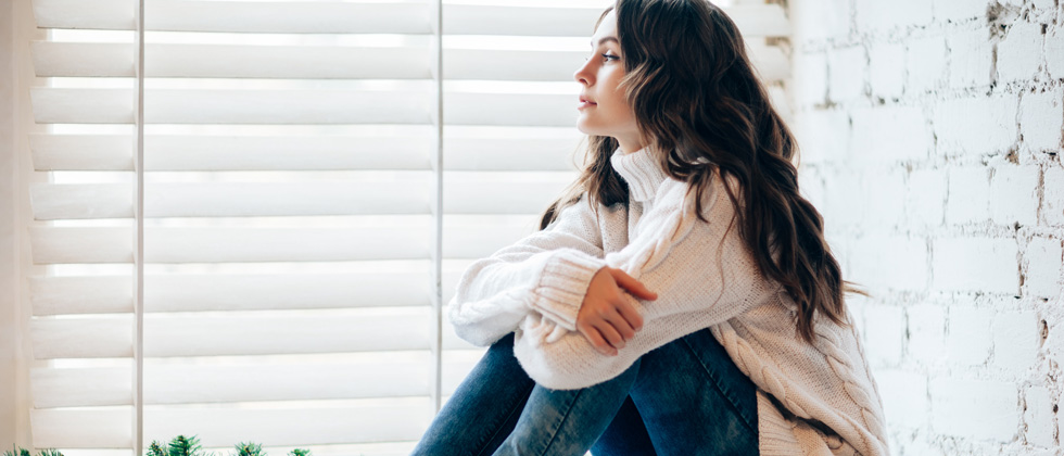 Woman looks out the window and thinks about how to get over ex