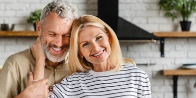 Older happy couple standing in their home holding each other
