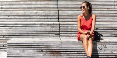 Pretty woman smiling and sitting alone on a park bench