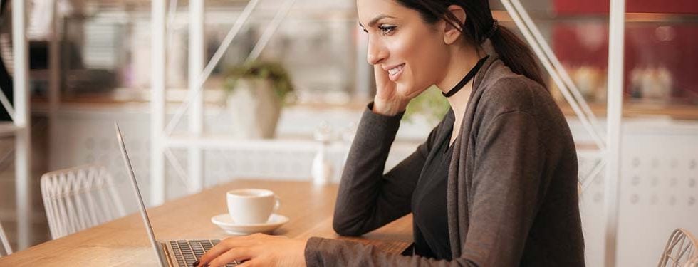 A woman sitting at a cafe working on her laptop