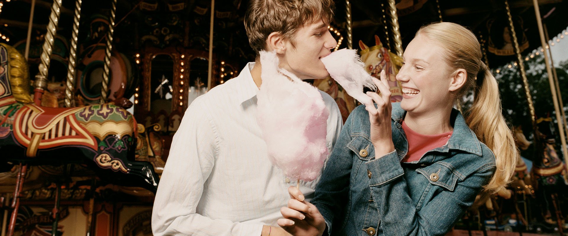 Man and woman eating cotton candy together and laughing as example how to flirt