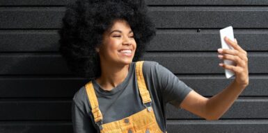 A young woman taking a selfie with a big smile on her face