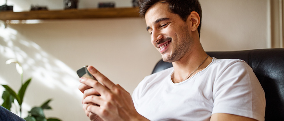 Man on mobile smiling as an example of what to text after the first date