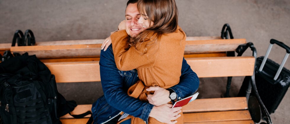 Man sitting on a bench with a woman on his lap as a symbol of how long-distance relationships can work.