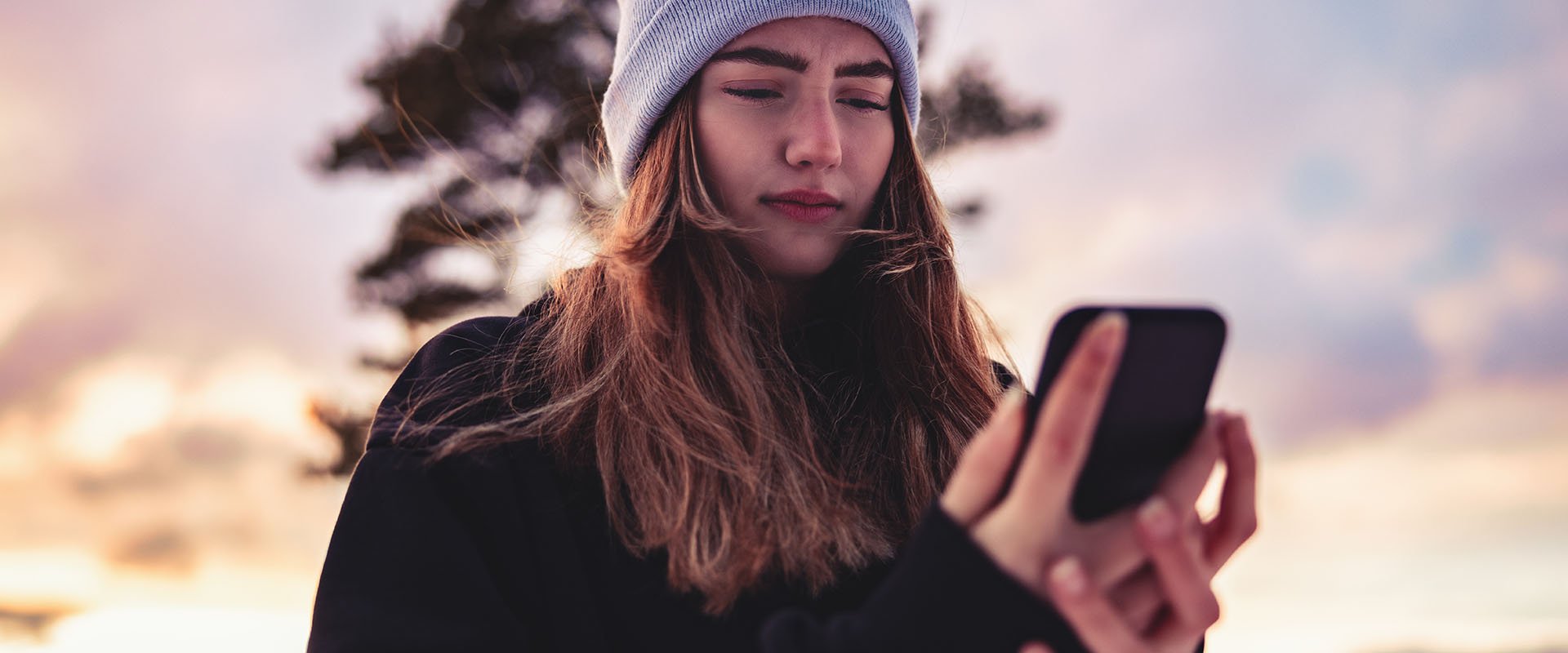 Woman looks hurt at her cell phone as symbol for dating multiple people