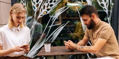 Man and woman both sitting on cell phone as symbol for dating red flags