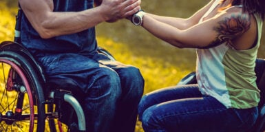 A couple in each in wheelchairs holding each other's hands