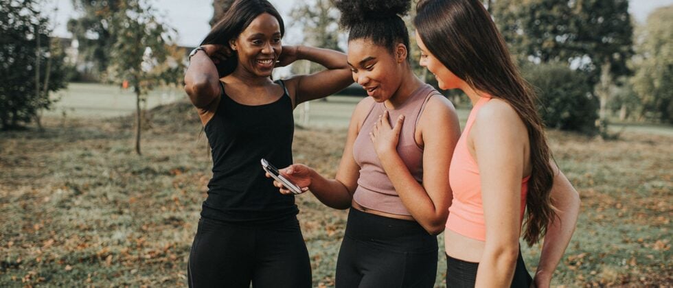 Two women looking together at a cell phone as a symbol for how to successfully start a conversation on a dating app