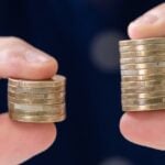 Someone holding two stacks of coins - one bigger than the other
