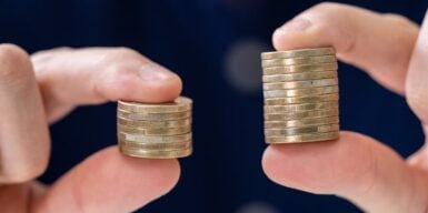 Someone holding two stacks of coins - one bigger than the other