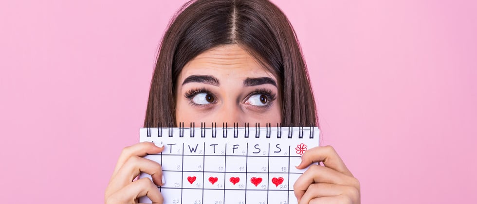 Woman holding a calendar with a date marked for every day that week