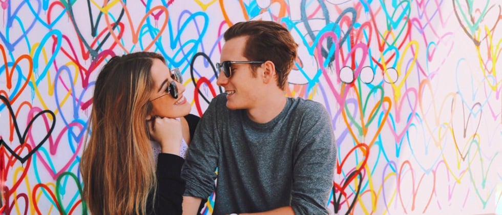 A couple having an intimate moment in front of a wall of hearts