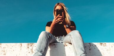 Woman sitting on wall with cell phone in hand as symbol for online dating safety