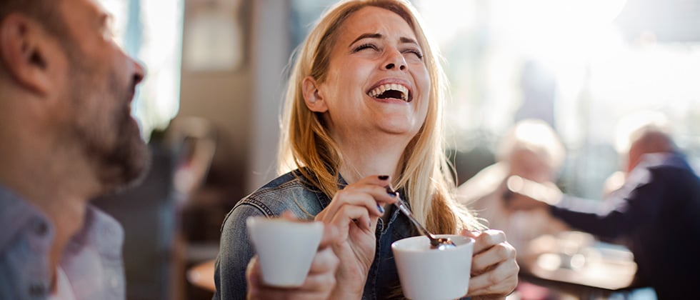 Man and woman drinking coffee and laughing as example for second date ideas