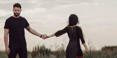 Couple in a field holding hands but walking away from each other