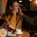Man and woman in cafe, man caresses her face and she smiles as an example of the question does he like me
