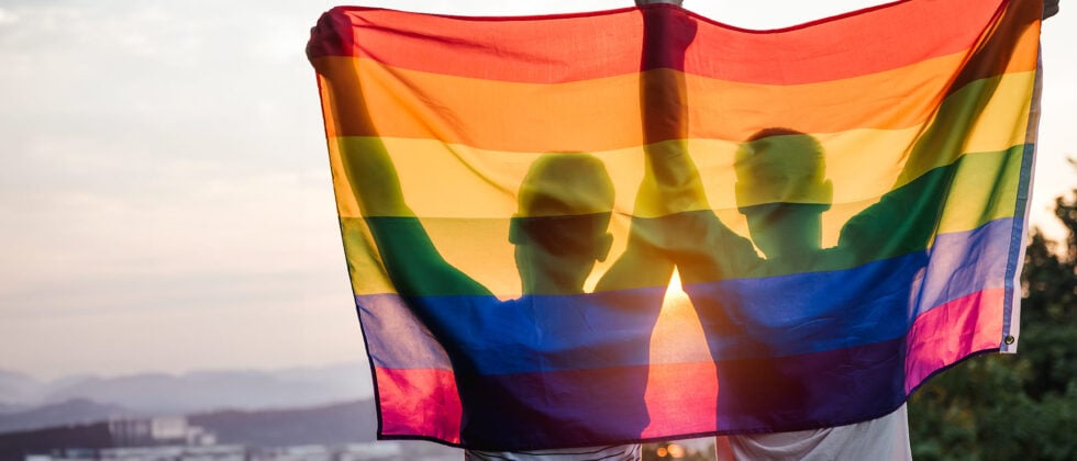 Two people hold up the lgbtq flag