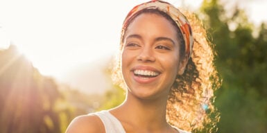 A woman with a huge smile standing under a beaming sun