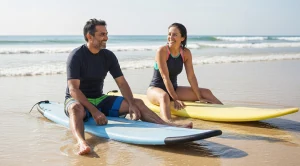 A couple sitting on surf boards at the beach.