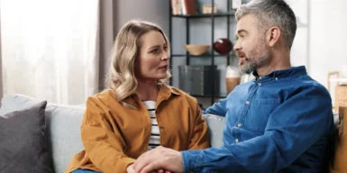 A couple sitting on their couch holding a conversation.
