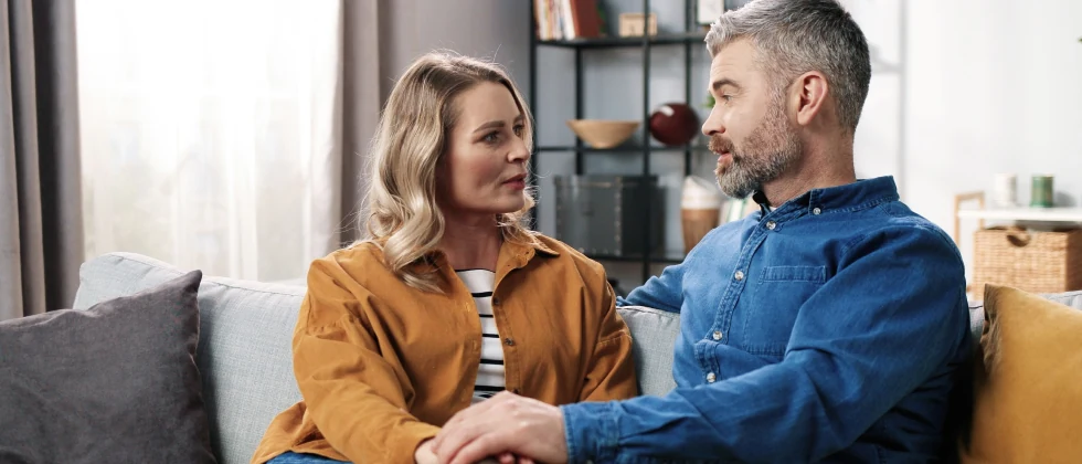 A couple sitting on their couch holding a conversation.