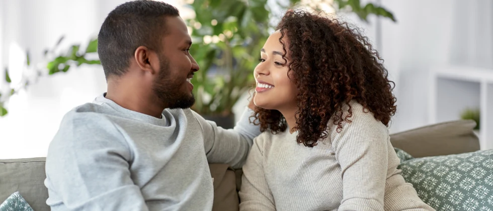 Couple sitting on a couch having a nice conversationg both smiling