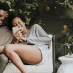 A couple sitting on a bench in the garden laughing together.